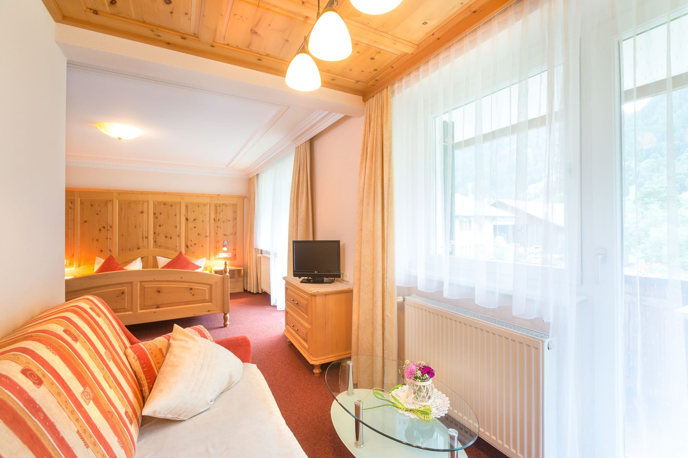 Helles Wohn- und Schlafzimmer mit Sitzecke und großem Fenster